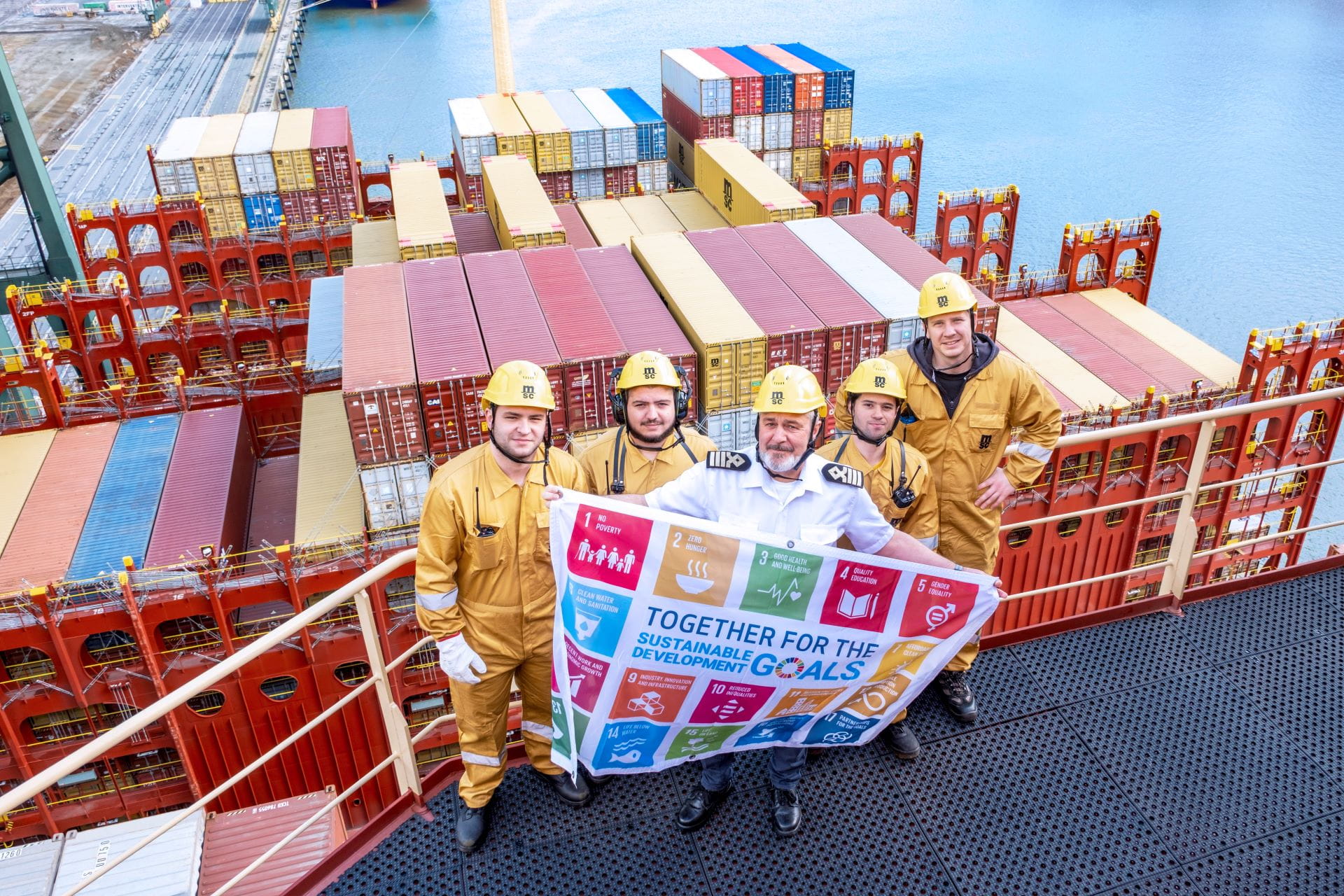 Vessel crew and captain on ship holding the Sustainability Development Goals Flag