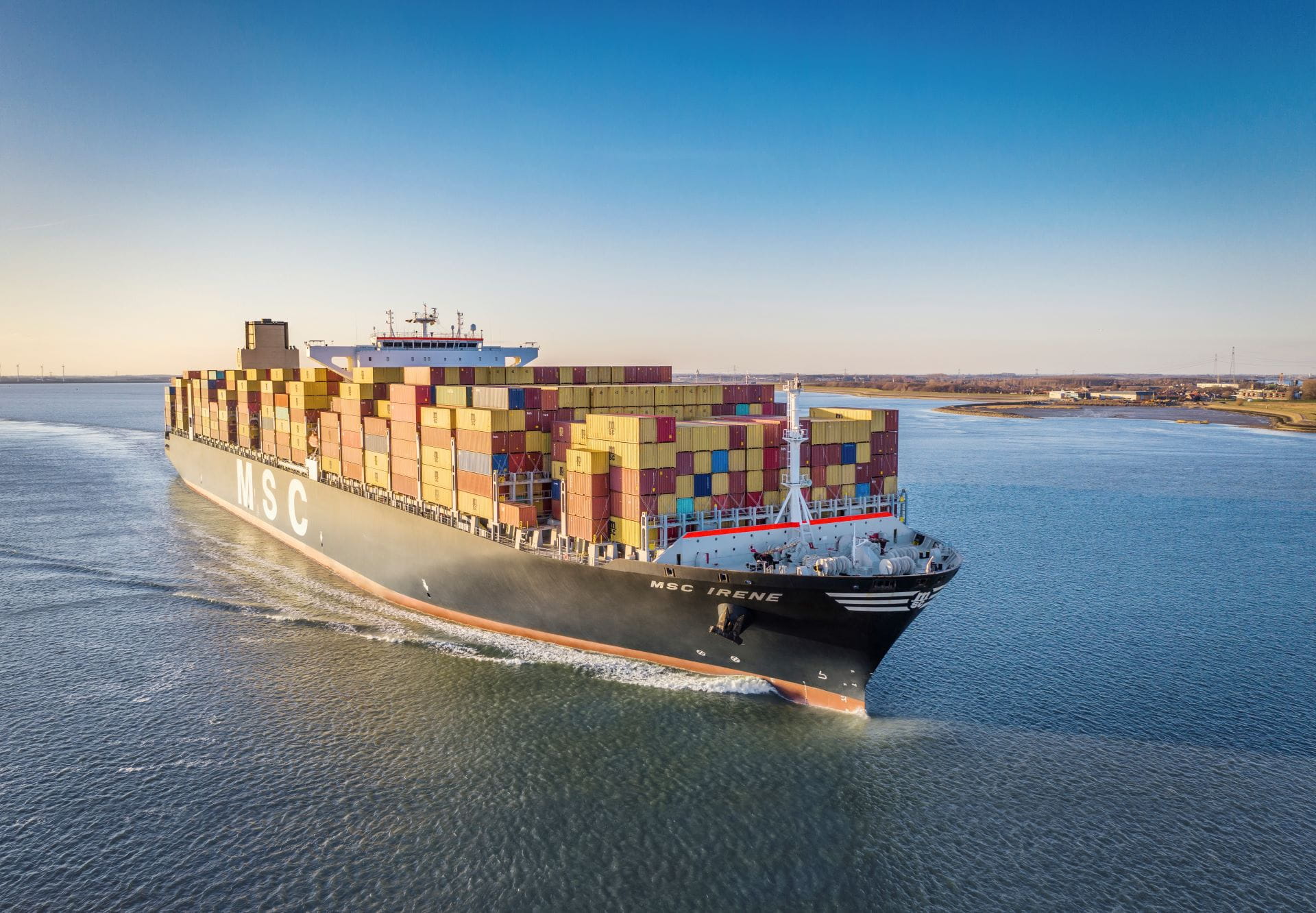 An MSC cargo ship navigating through serene waters, under a clear blue sky